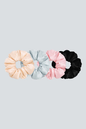 Set of soft silk scrunchies in pastel pink, sky blue, and classic black on a neutral background