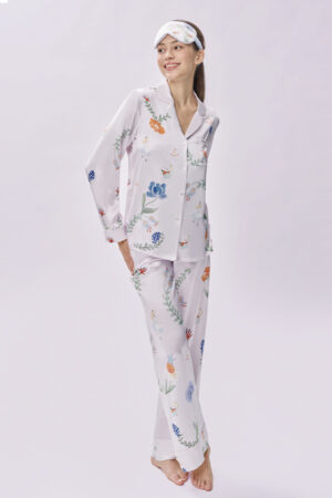 Woman smiles against a clean backdrop while wearing MANITO Alice Fantasy Forest Pajama Set with a matching silk eye mask.