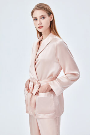 The elegant woman wearing the Elite Silk Robe has her hands in pockets and a belt around her waist for added design.