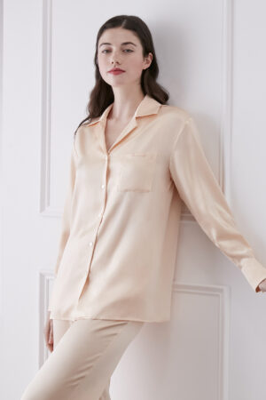 Model wears Resort Women's Pajama Set in Orange silk, showcasing lapel shirt with front pocket and smooth satin finish.