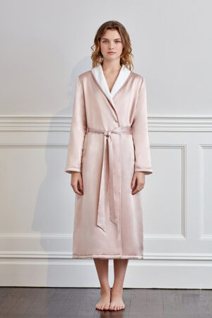 Elegant woman standing in a pink silk terry robe with contrasting white trim.