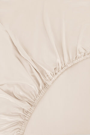 Close-up of elasticized corner detailing on MANITO Authentic Silk Fitted Sheet in ivory.
