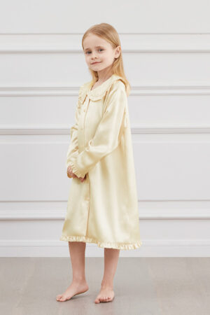 A girl in MANITO Yellow Cloud Silk Nightgown with long sleeves and ruffle trim.