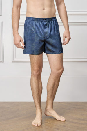 Model wears Cube Men's Shorts in navy soft silk, featuring geometric dot and line patterns for relaxed sleepwear comfort.