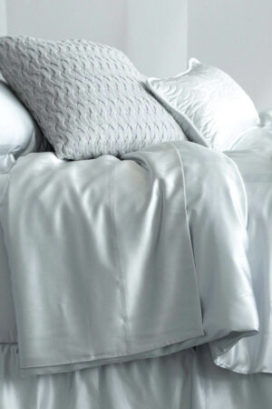 Elegant 22 silk duvet cover, softly draped over a bed with textured pillows, highlighting the smooth finish and luxurious quality.