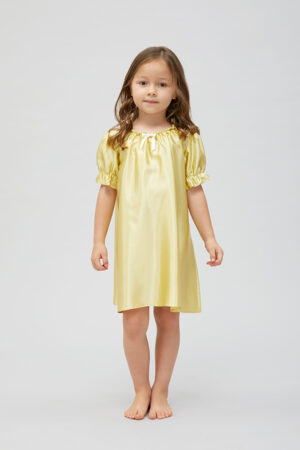 Little girl in an elegant yellow silk nightgown with ruffled sleeves and neckline.