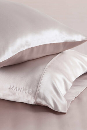 Close-up of soft pink Silk Pillowcase Set with embroidered logo of MANITO.