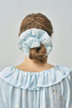 Back view of model wearing blue MANITO DISNEY Alice Daisy Puff Hair Scrunchy with voluminous silk design.