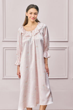 Woman in a pink MANITO DISNEY Daisy Nightdress with soft gathers and collar, standing in front of a pastel wall.