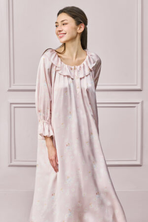 Woman wearing a pink MANITO DISNEY Daisy Nightdress with ruffled neckline and relaxed sleeves conveys a joyful mood.