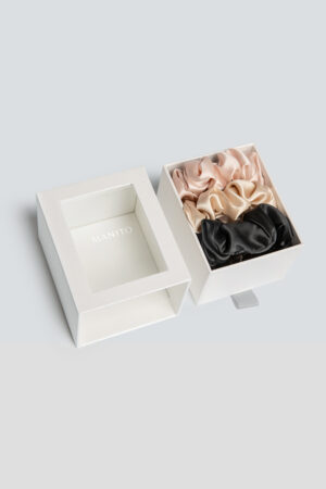 3 Pack Large Silk Scrunchie Set in pink, champagne, and black displayed in a box, offering a silky touch for effortless hair styling.