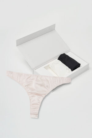Black and white Tacetto briefs stacked inside the opened gift box with a pink one displayed in front, emphasizing sleek silk comfort.