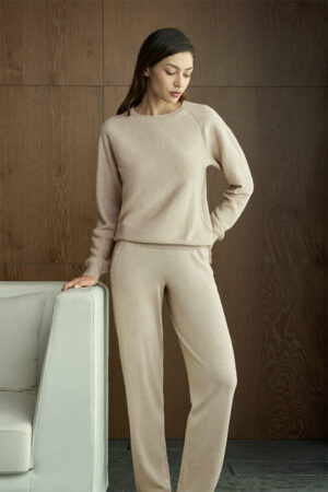 Woman in beige Terra Knit Set stands by a sofa, highlighting the knit's plush softness and delicate texture.