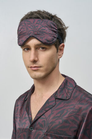 Model wears Tropical Leaves Men's Eye Mask with matching silk pajama, highlighting the delicate pattern and comfortable fit.