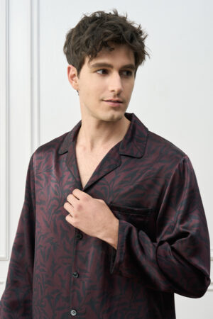 Close-up of model in Tropical Leaves Men's Pajama Set, highlighting smooth silk fabric and matte black buttons.